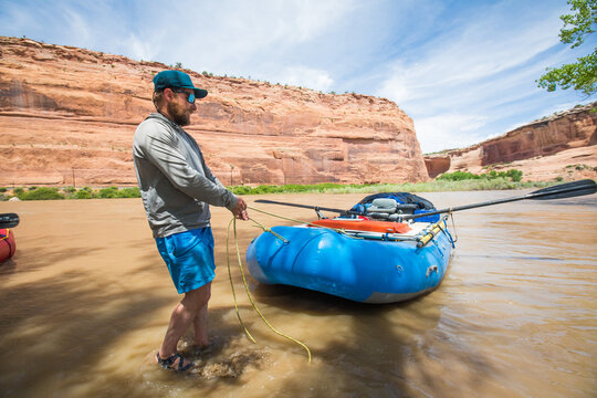 Man pulls inflatable raft ashore in desert canyon