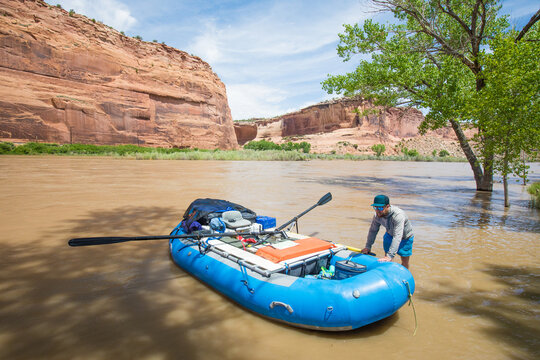 Man preparing a blue raft for a desert river trip