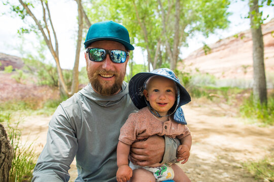 Happy father holding his smiling toddler son outdoors