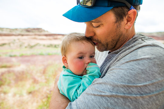 Father tenderly kisses his babys forehead outdoors