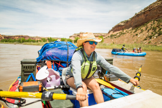 Smiling woman guides a raft down a desert river