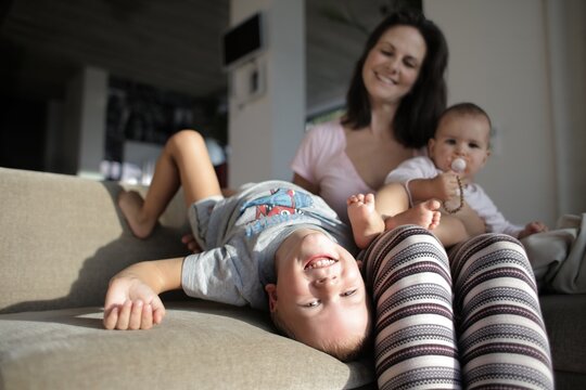 Smiling mother relaxing on couch with two children