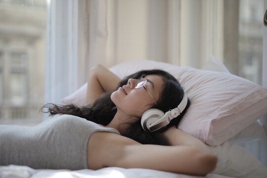 Young woman relaxing in bed with headphones