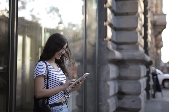 Happy woman uses a digital tablet on a city street