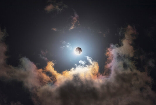 Partial moon eclipse filtered by dramatic moving clouds