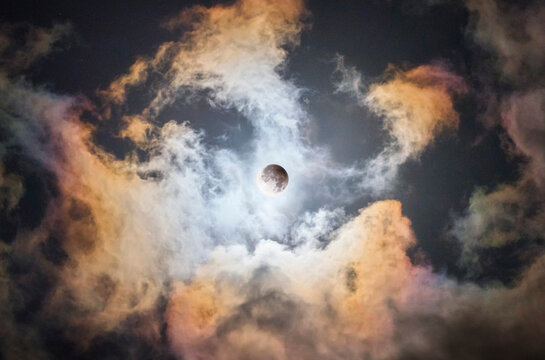 Partial Lunar Eclipse Behind Dramatic Colorful Clouds in the Night Sky