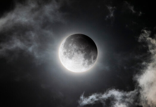 Full moon partial lunar eclipse glowing through dramatic night sky