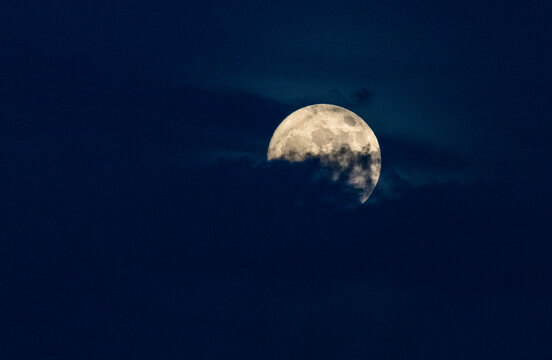 Majestic full moon partially obscured by dark atmospheric clouds