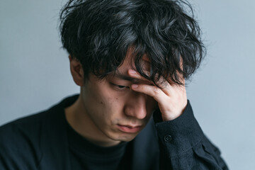 Fototapeta premium 悩みを抱えてうつむく若い男性のポートレート