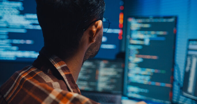 Close up young Male programmer hands typing on keyboard in dark home office at night. AI technology, cybersecurity, software developer, freelance innovation, database system, digital network concept.