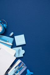 Vertical Blue Stationery Flat Lay with Blank Grid Notebook, Alarm Clock, Pencil Case, and Sticky...