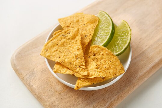 Corn Tortilla chips with slices of lime on a white plate