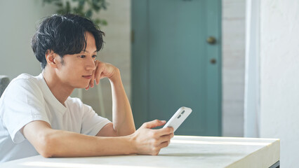 笑顔でスマホを使う男性。アプリ、SNS、動画、ゲーム、リラックス、検索、web、DX、AI、配信 © metamorworks