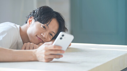 笑顔でスマホを使う男性。アプリ、SNS、動画、ゲーム、リラックス、検索、web、DX、AI、配信 © metamorworks