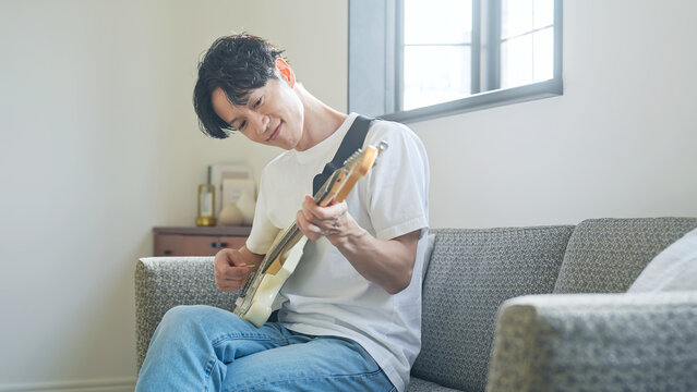 エレキギターを弾く男性。音楽、楽器、演奏、練習、趣味、バンド、音楽家、ミュージシャン、ギタリスト