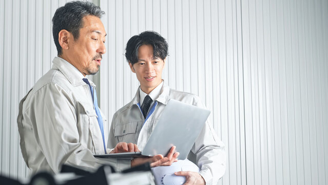 打ち合わせする男性作業員のグループ。建設、工事、工場、業者、相談、会議、DX、修理、点検、建築、内装