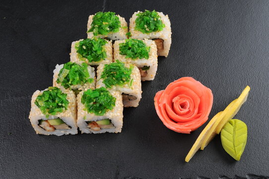 Sushi Rolls with Seaweed Salad on Dark Stone Surface