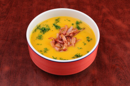 Creamy Pumpkin Soup Topped with Bacon and Dill in Bowl