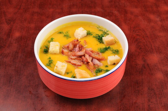 Bowl of Pumpkin Soup with Bacon and Croutons on Wooden Table