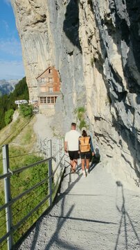 Switzerland showcases the stunning Aescher Ebenalp, where visitors hike along scenic paths. A couple of men and women are hiking in the Swiss Alps 