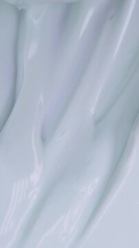 Vertical close up of stirring beauty whitening cream gently using a metal spoon. Smooth mixing texture, skincare product preparation for daily treatment.