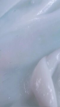 Top view of stirring white cream from close up. Moisturizing skin cream being smoothed and spread with a plastic spoon. Skincare product preparation concept.
