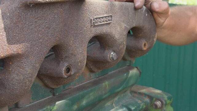 Mechanic tightening a nut on a rusty exhaust manifold