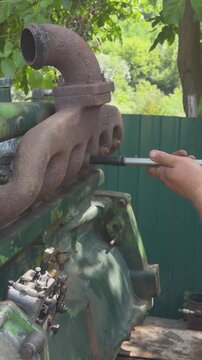 Mechanic tightening old diesel engine exhaust manifold bolts