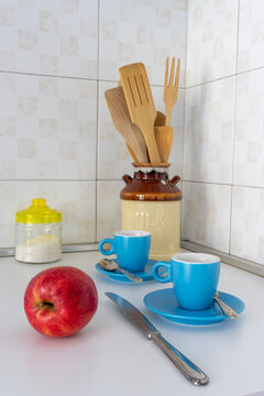 Elegant kitchen still life with apple, coffee cups and wooden utensils