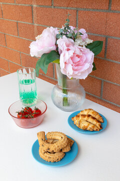 Elegant floral and breakfast still life with peonies, strawberries and croissants