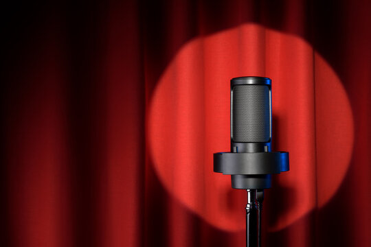 Microphone with spotlight on red stage curtain.