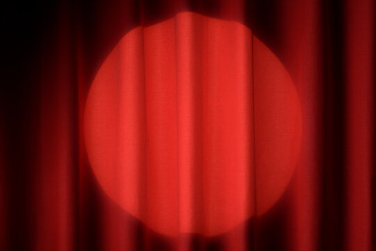 Red curtain with a bright spotlight shining on stage.