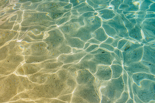 Sunlight shimmering on sand bottom through clear ocean water