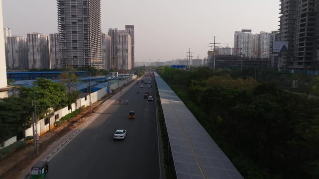 solar cycle track with ORR service road, vehicles and high-rise buildings at Narsingi, nanakramguda, hyderabad, telangana, india. day time, push in shot, drone shot, 4k.