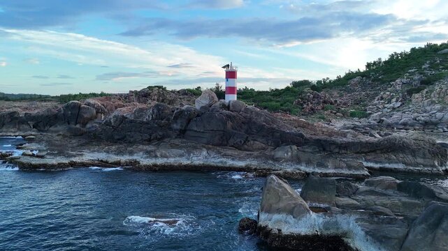 Drone footage captured at low altitude above the sea approaching Ganh Den Lighthouse in Dak Lak (formerly Phu Yen) Province, Vietnam. Flying close to isolated rocky outcrops offshore