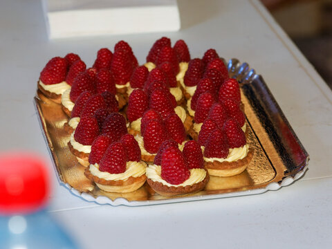 Plateau de mini tartelettes aux framboises et cr&egrave;me p&acirc;tissi&egrave;re servi lors d'une r&eacute;ception, d'un mariage, d'un bapt&ecirc;me ou d'un cocktail