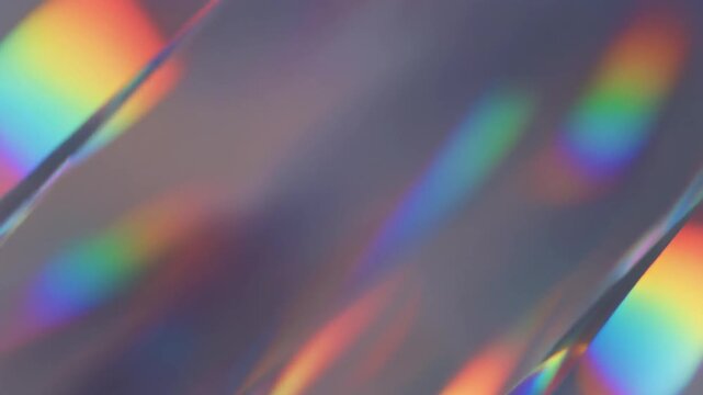 Macro view of holographic diffraction film displaying flowing rainbow colors and spectral reflections under soft studio lighting, creating a refined futuristic abstract background.