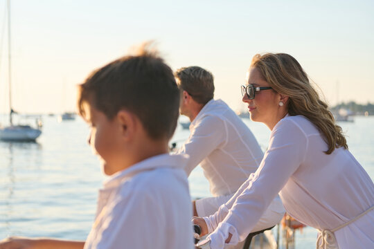 Family Enjoying Boating At Marina During Sunlit Summer Vacation Together
