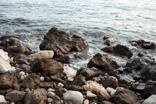 Nature background texture with sea water waves and rock stones close up. Summer vacation time.