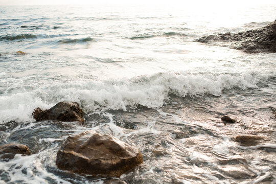 Nature background texture with sea water waves and rock stones close up. Summer vacation time.