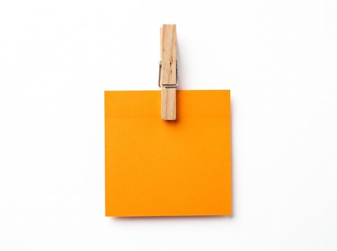 Blank orange square sticky note mockup held by a wooden clothespin clip isolated on a white background for message, reminder, or office memo. Minimalist paper stationery peg and notice element.