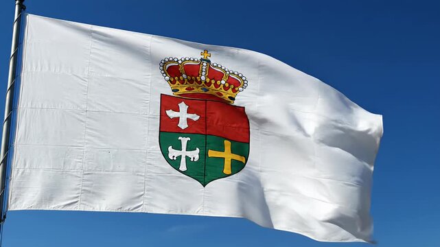 Waving white flag with a detailed coat of arms and crown against a clear blue sky, representing sovereignty, national identity, or regional pride