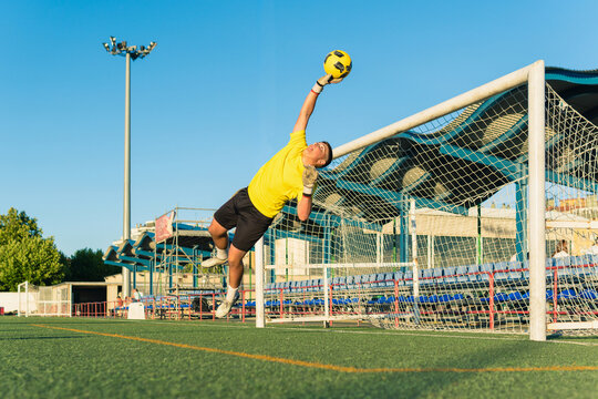 Goalkeeper jumping high saving soccer ball from scoring