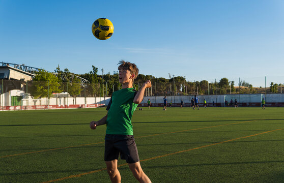 Young boy heading yellow soccer ball during training