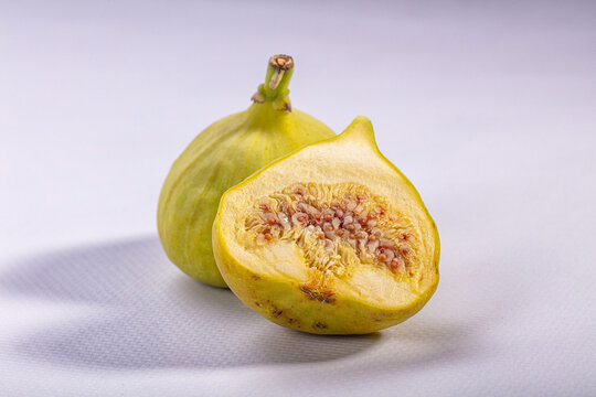 Fresh fig sliced open showing juicy interior on white textured surface