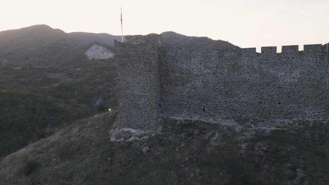 The drone approaches the ancient stone walls of Maglic fortress, nestled in the mountains of Southwestern Serbia at twilight.