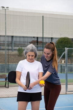 Two women practicing pickleball on a court, learning the game