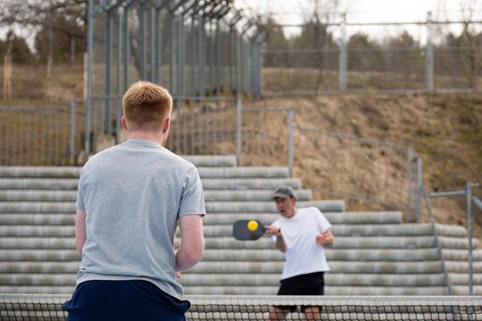 Two men competing in an energetic pickleball game outdoors
