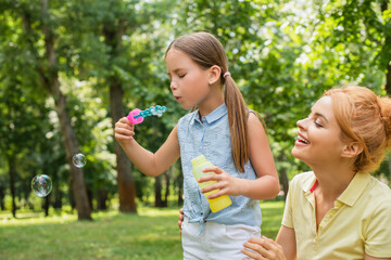 Fototapeta premium Joyful moments at the playground as mother and daughter share a fun day filled with soap bubbles