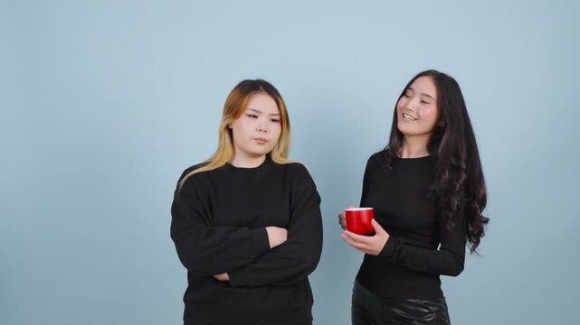 Annoyed young woman listening to her talkative friend holding a mug